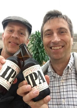CEO Milosz Bazela and Head of Products Department Stano Dzavoronok sharing bottles of IPA beer.