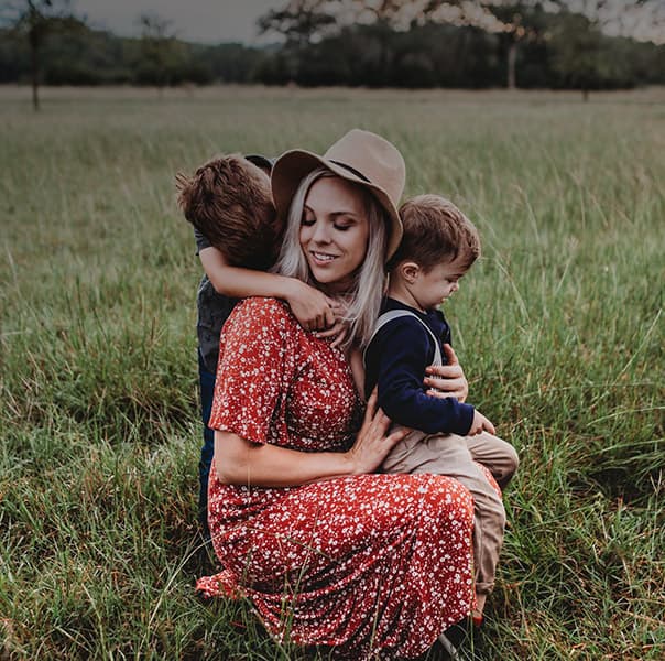 A woman hugged by her children.